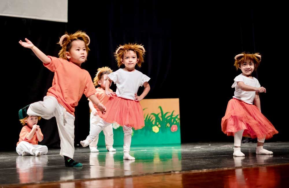 A group of young children are dancing on a stage.