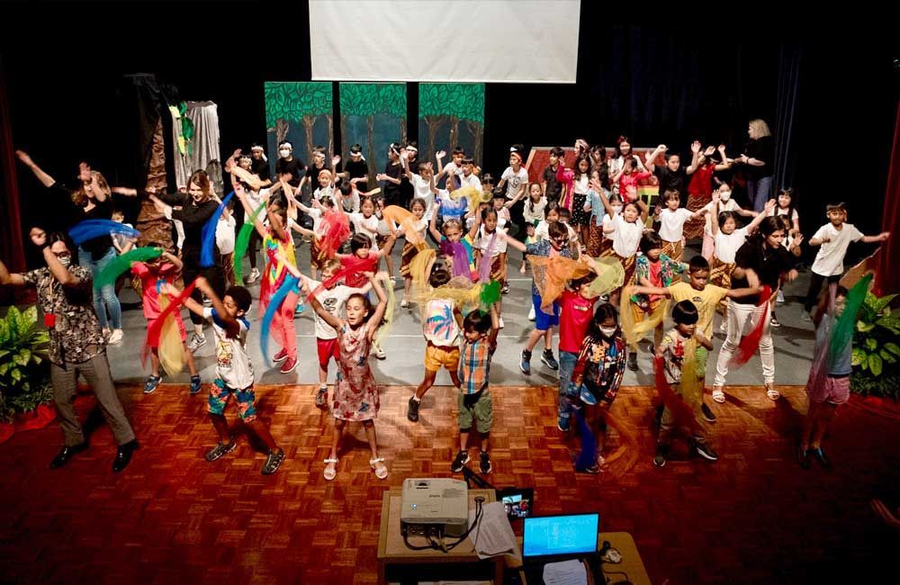 A large group of children are dancing on a stage.