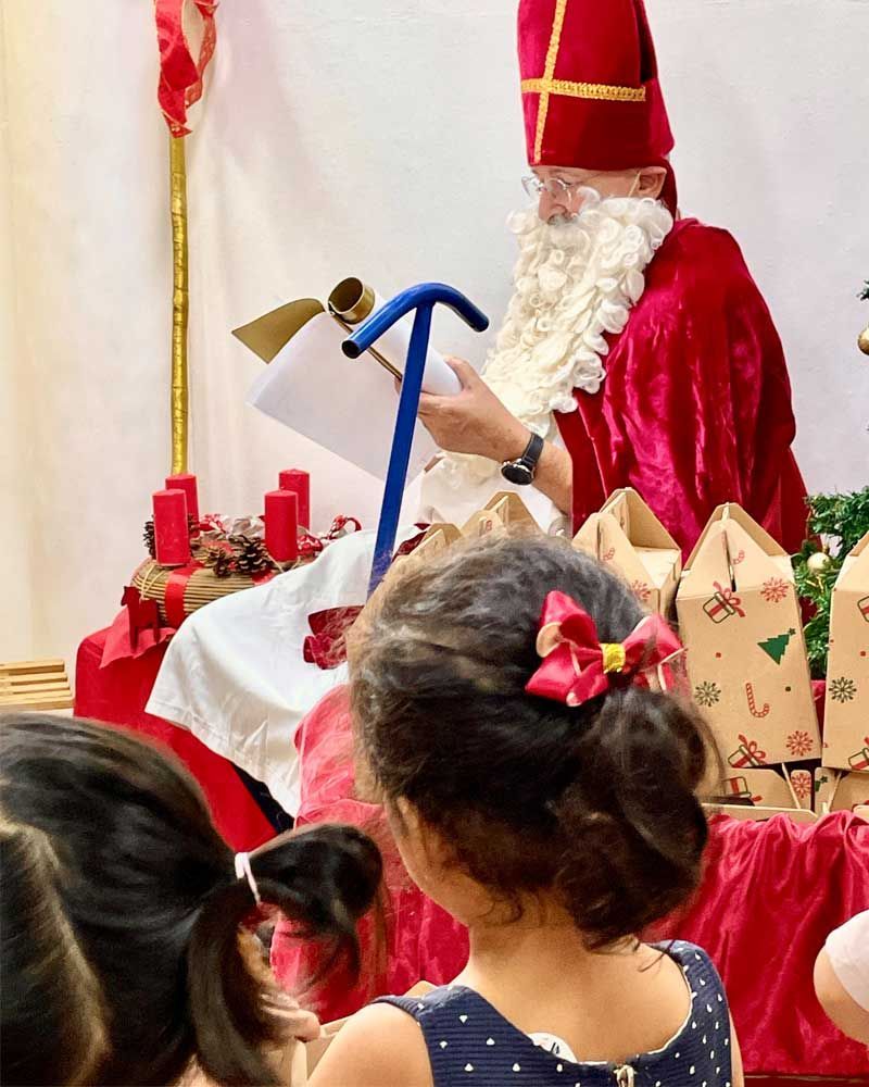 A little girl with a bow in her hair is looking at a man dressed as santa claus
