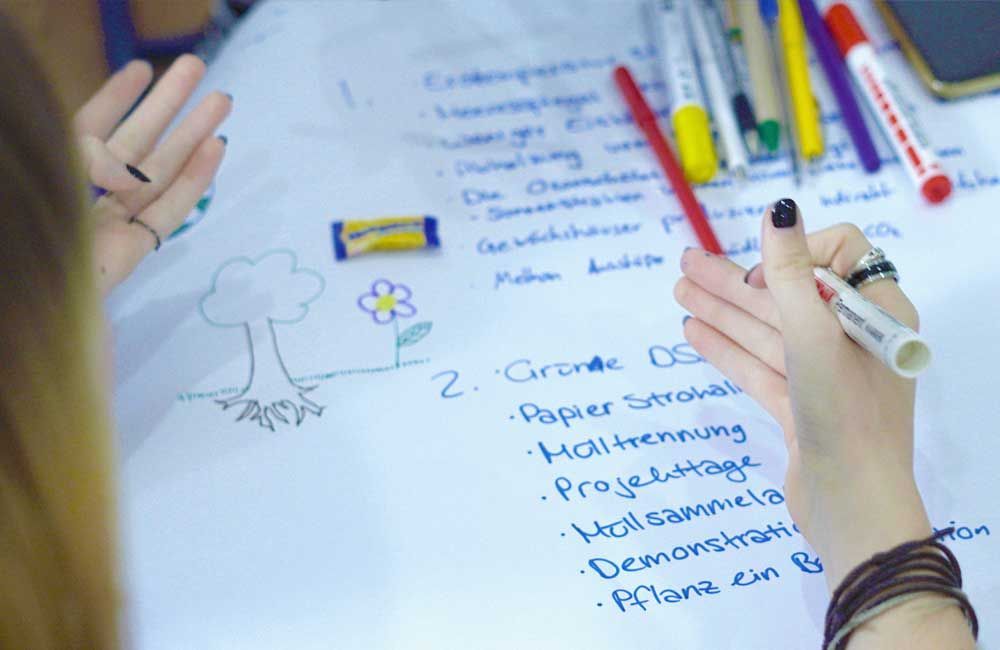 A person is writing on a piece of paper with markers.
