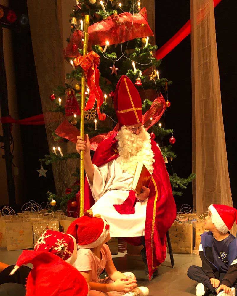 A man dressed as santa claus is sitting in front of a christmas tree