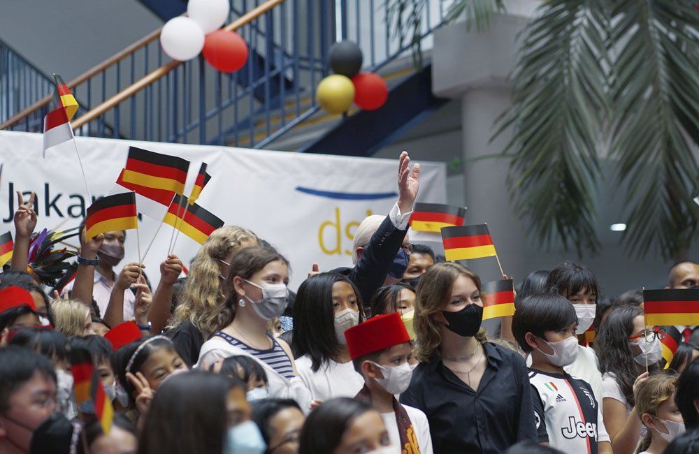 A crowd of people wearing masks and holding german flags.