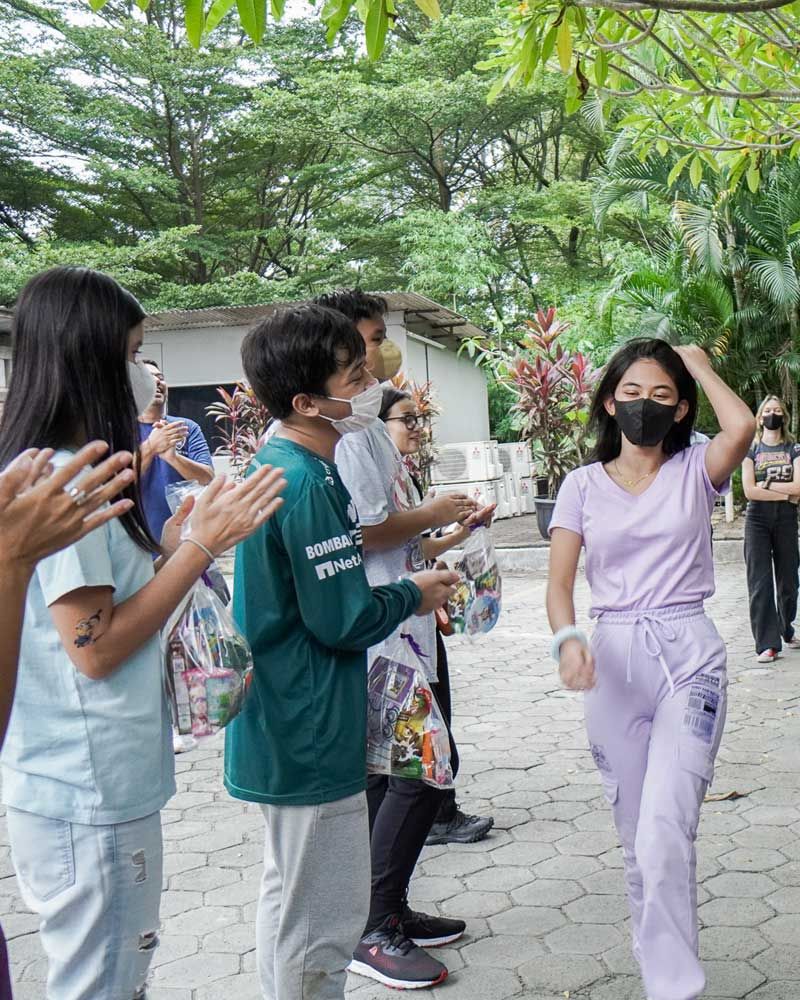 A group of people wearing face masks are clapping and applauding.