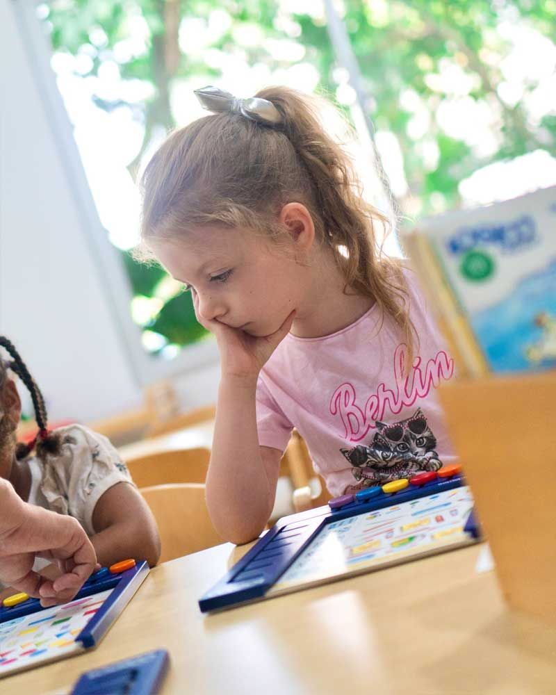 A little girl is sitting at a table playing a game.
