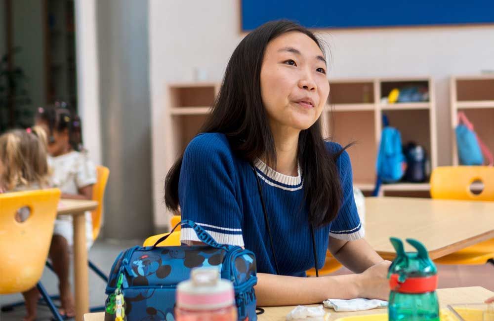 A young girl is sitting at a desk in a classroom.