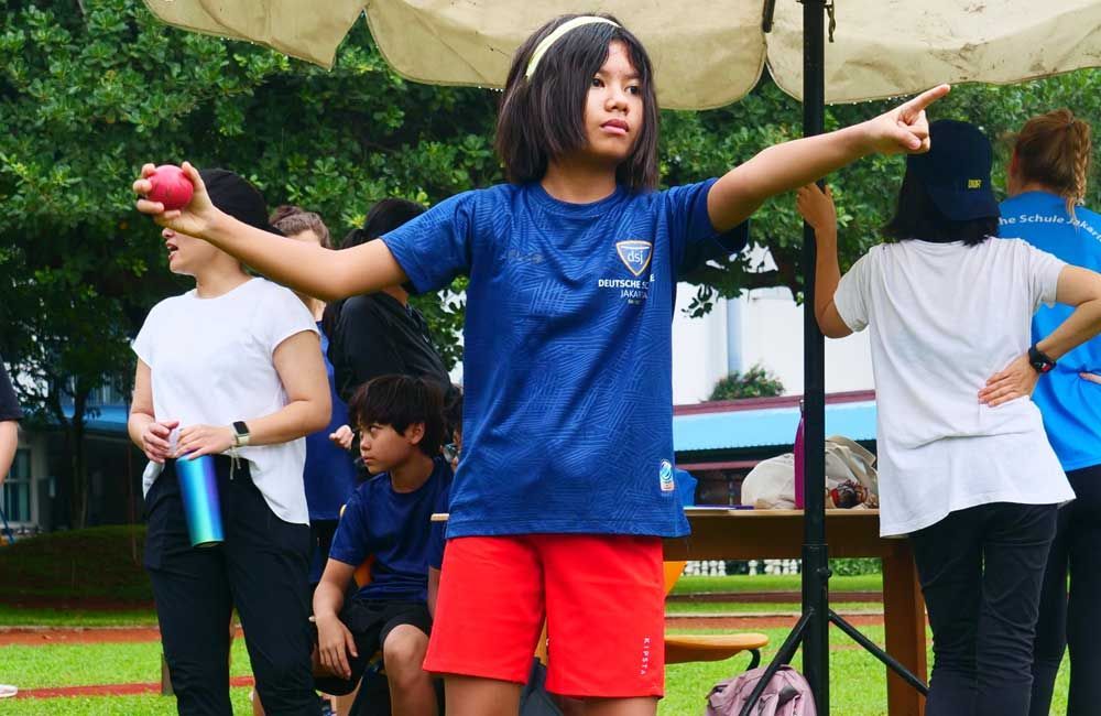 A girl in a blue shirt and red shorts is pointing at something.