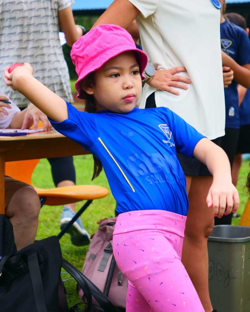 A little girl wearing a blue shirt and a pink hat