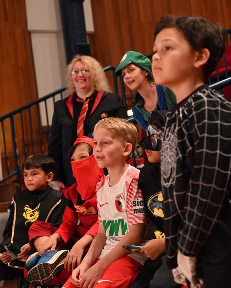 A group of children dressed in costumes are sitting in a row