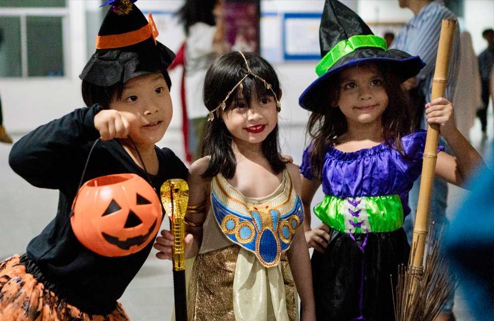 Three children dressed in halloween costumes are posing for a picture.