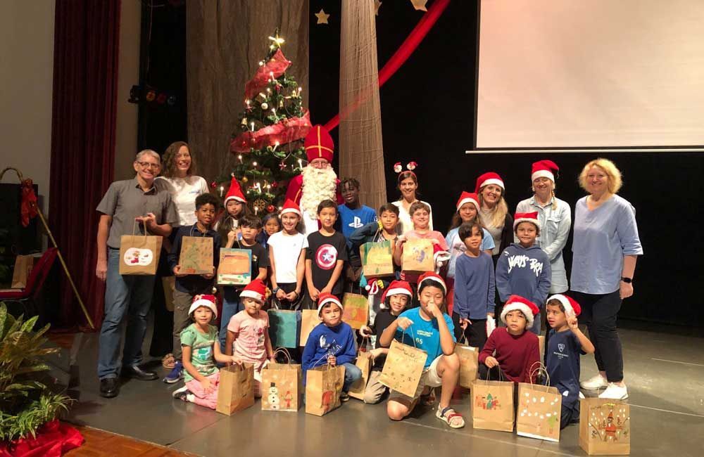 A group of children are posing for a picture in front of a christmas tree.