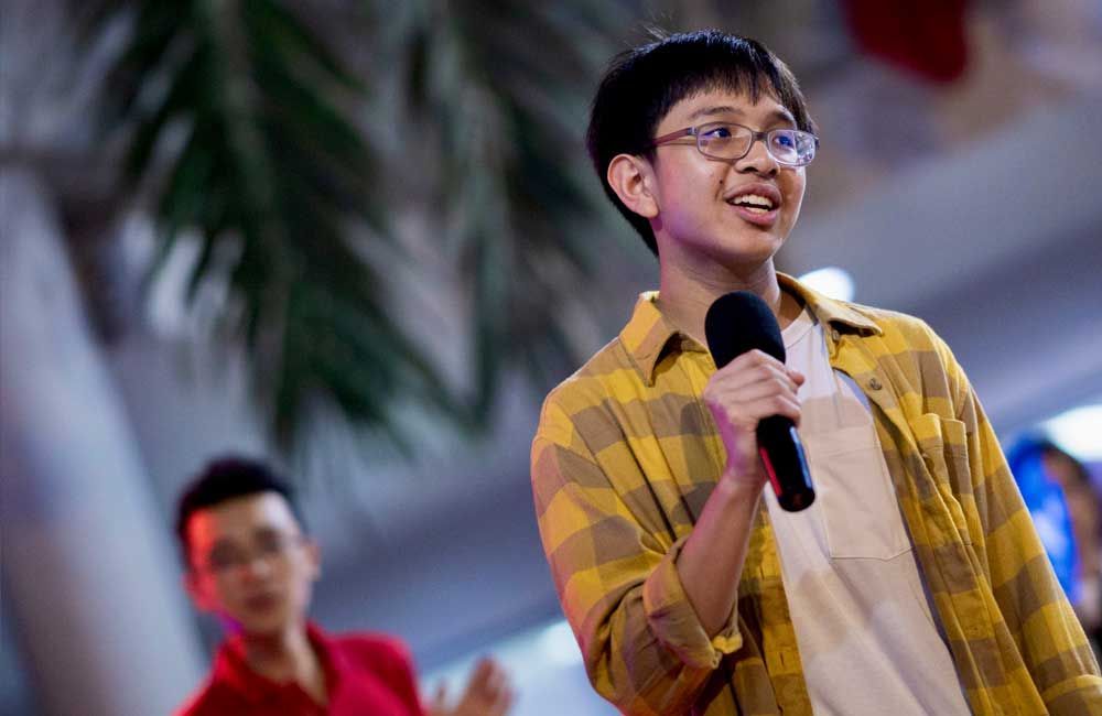 A young man is holding a microphone in his hand and smiling.