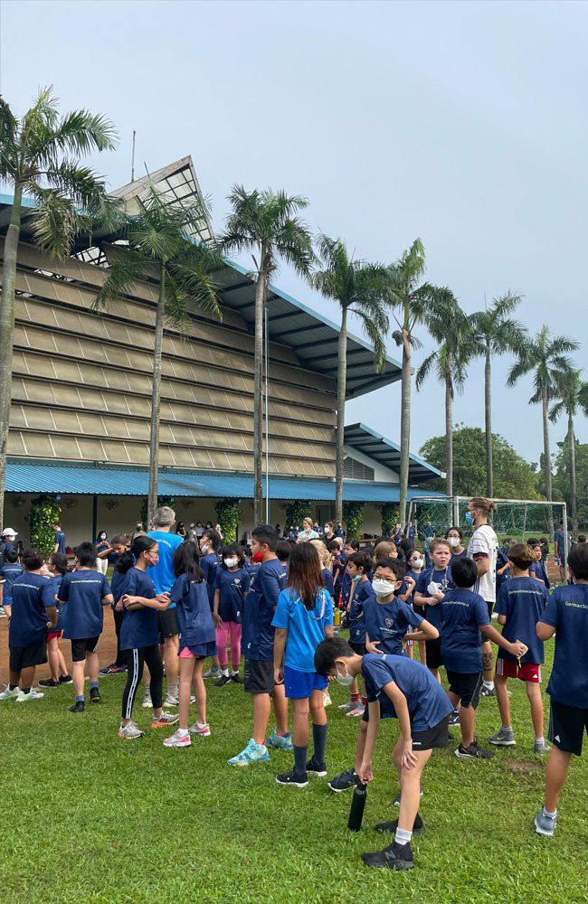 A group of children are standing in a field in front of a building.