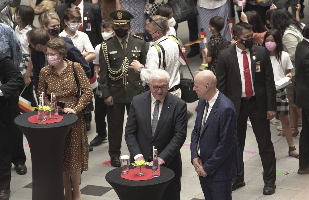 A group of people are standing around tables in a crowd.