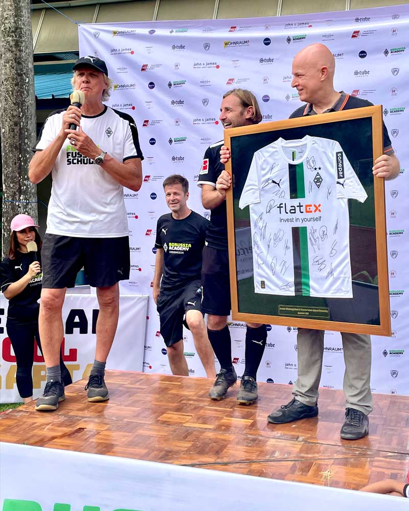 A man is holding a framed shirt that says flatex on it