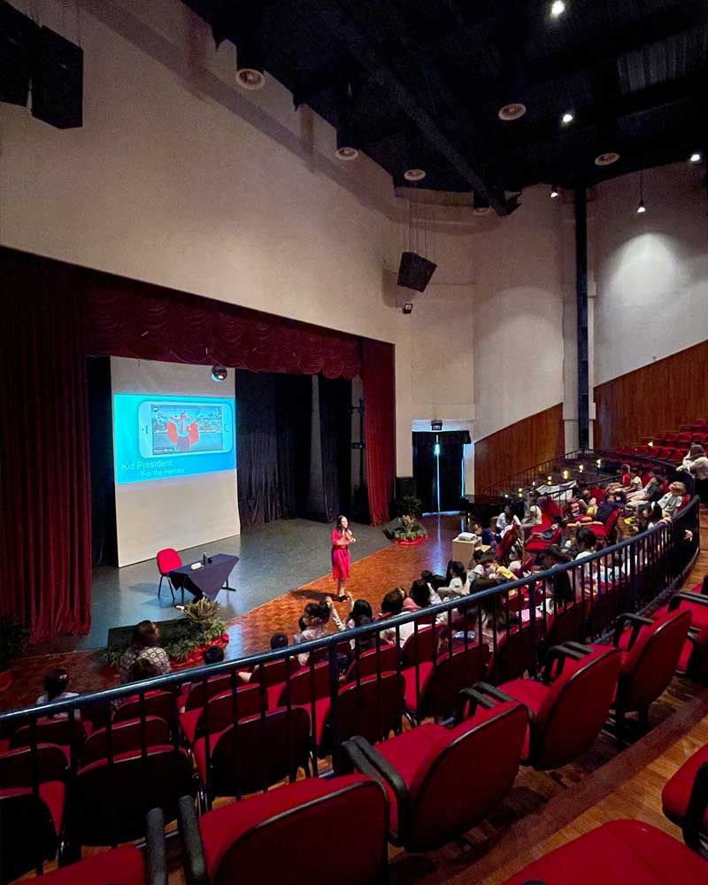 A woman is giving a presentation in a large auditorium