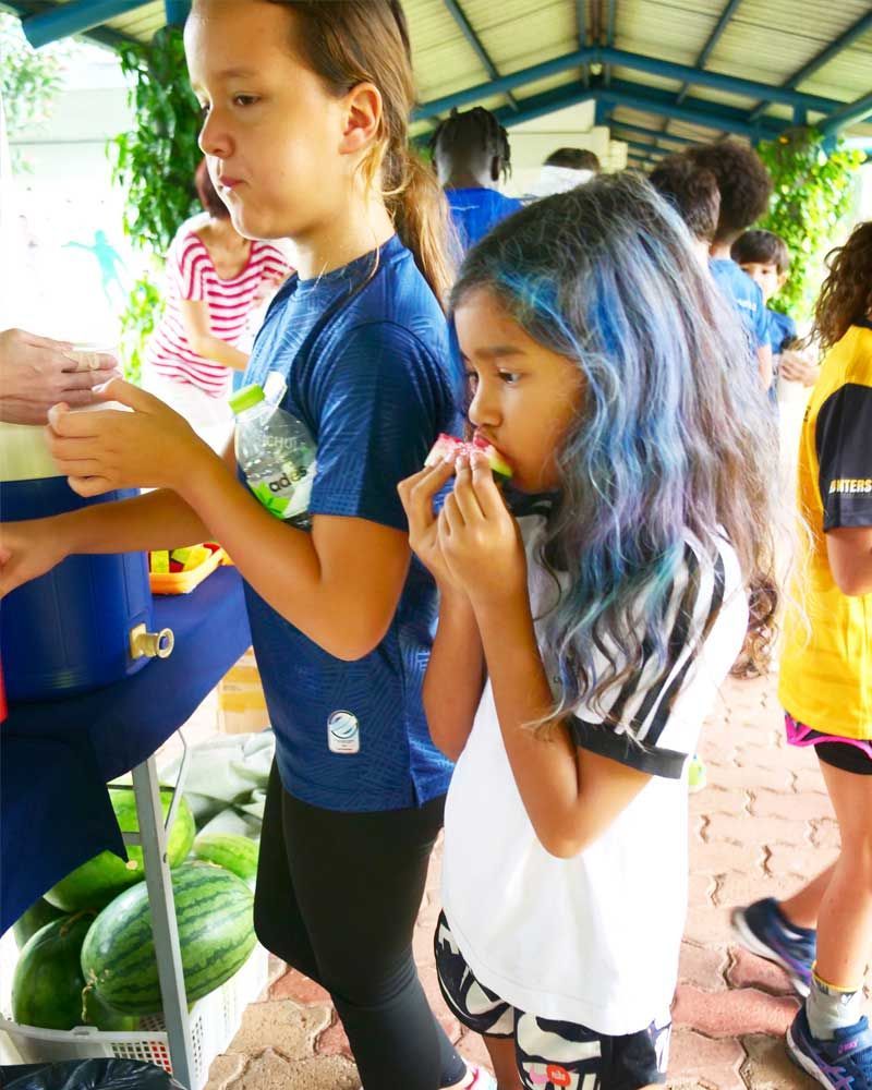 A girl with blue hair is eating a watermelon slice