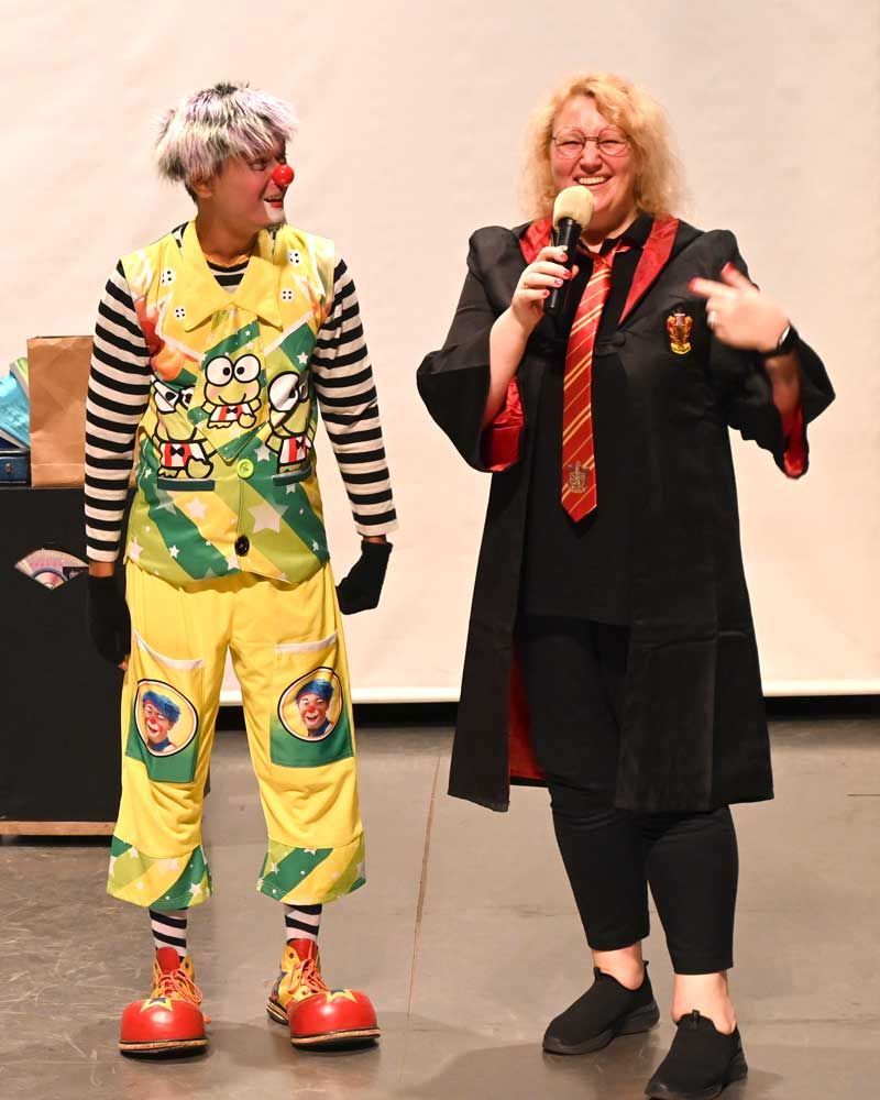 A woman in a harry potter costume stands next to a clown