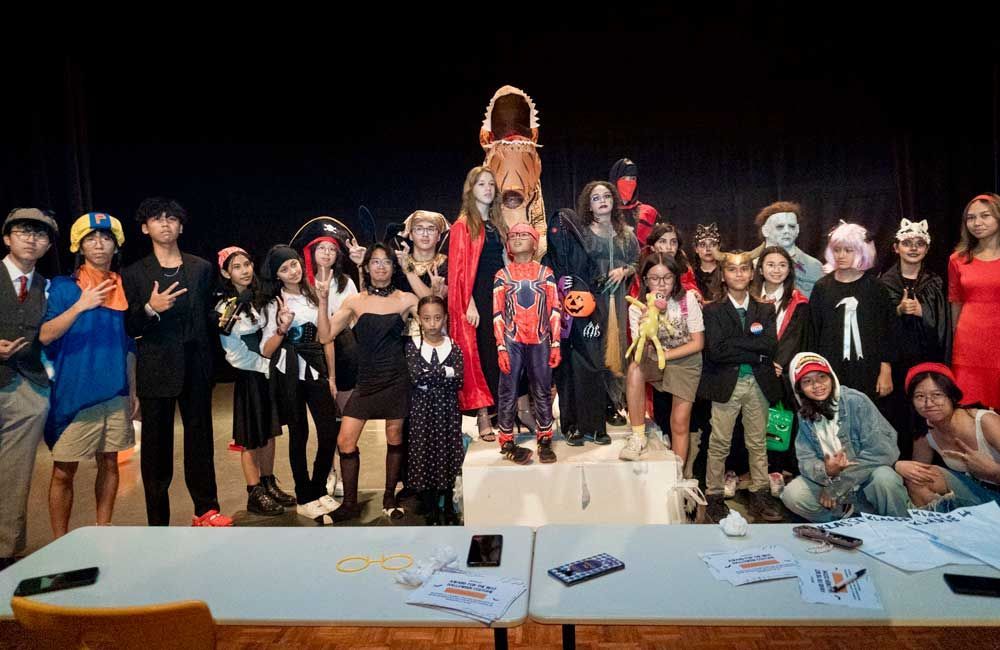 A group of children dressed in halloween costumes are posing for a picture.