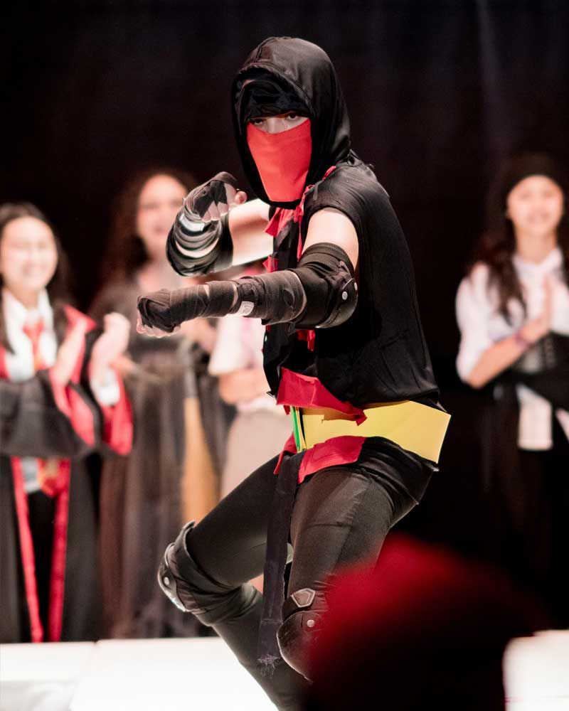 A person in a ninja costume with a red mask on their face