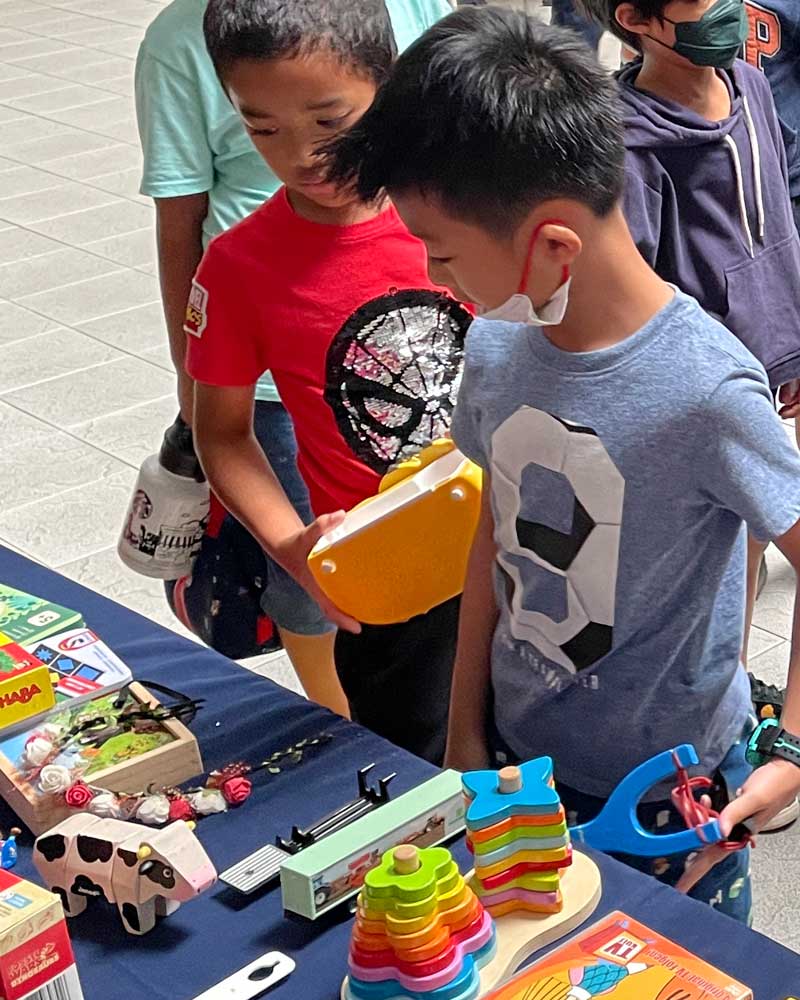 A group of young boys are looking at toys on a table.