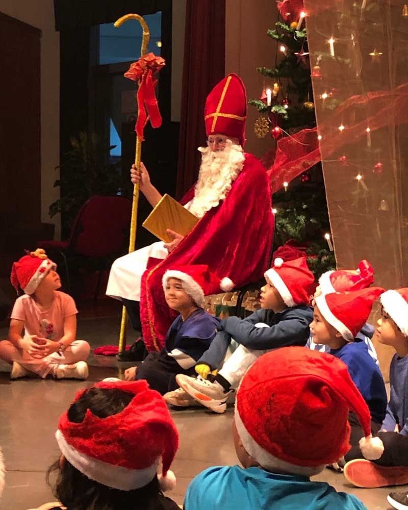 A group of children are sitting around a man dressed as santa claus
