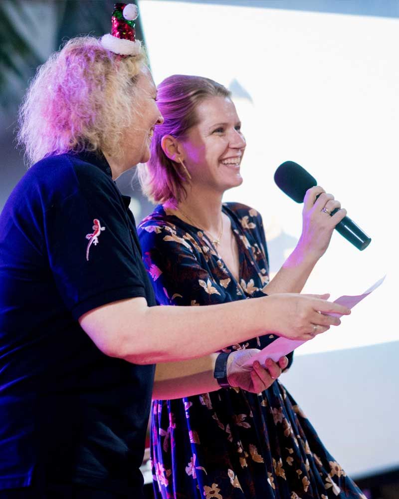 A man and a woman are standing next to each other holding microphones.