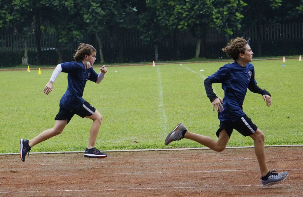 Two young boys are running on a track.