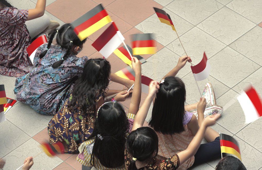 A group of children are sitting on the floor holding flags