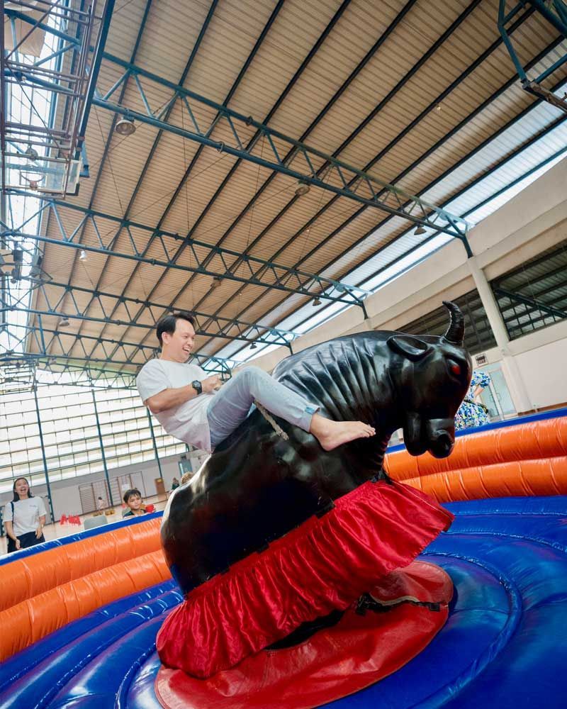 A man is riding a mechanical bull in a gymnasium.