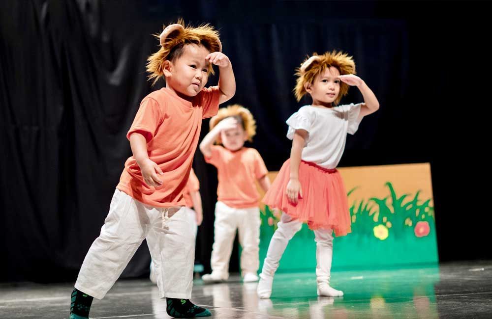 A group of young children are dancing on a stage.