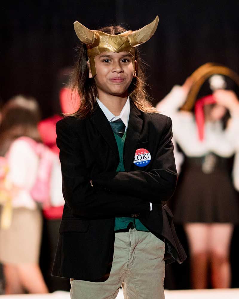 A young boy wearing a viking helmet and a badge that says local