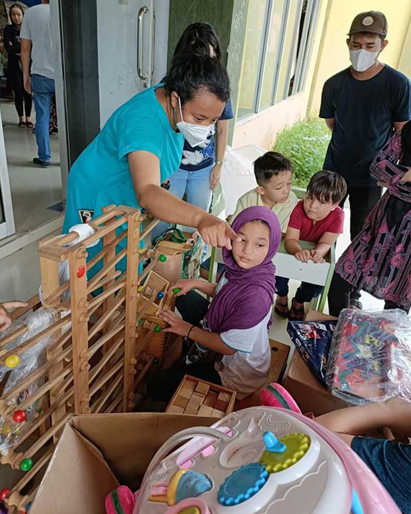 A woman wearing a mask is playing with a child.