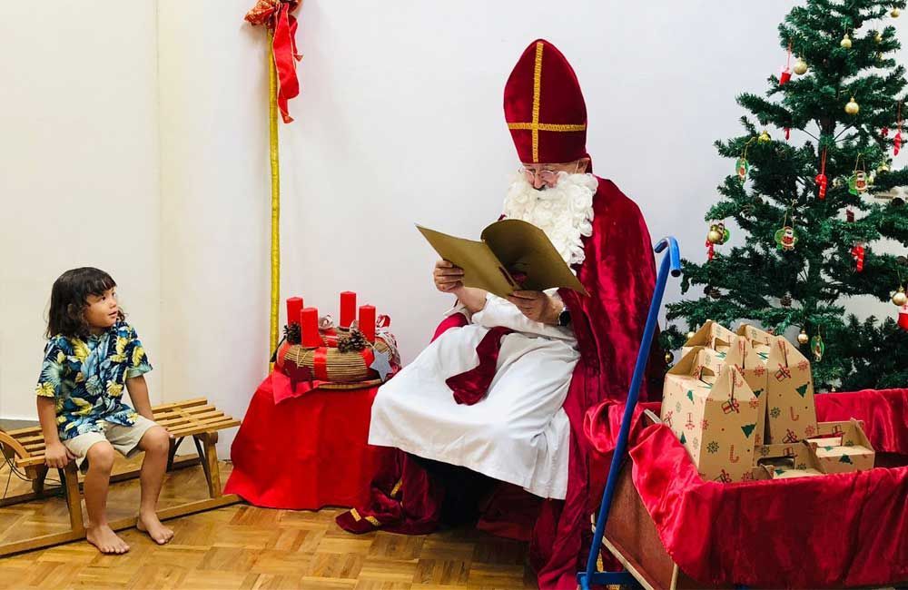 A man dressed as santa claus is reading a book to a child.