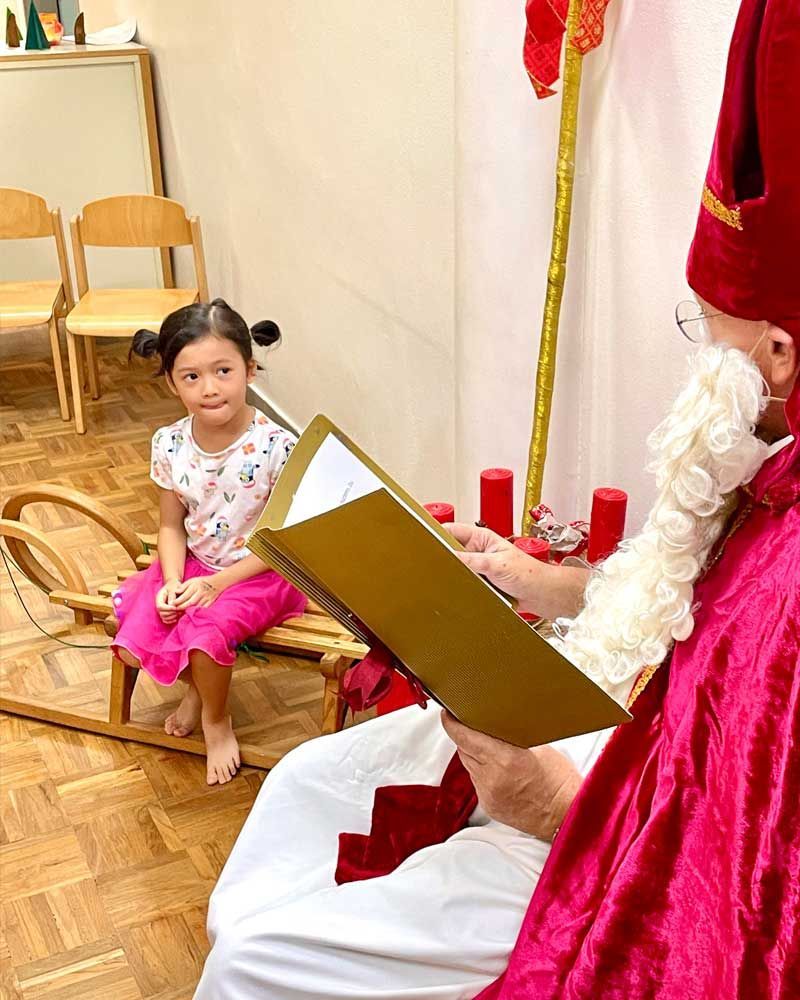 A man dressed as santa claus is reading a book to a little girl.