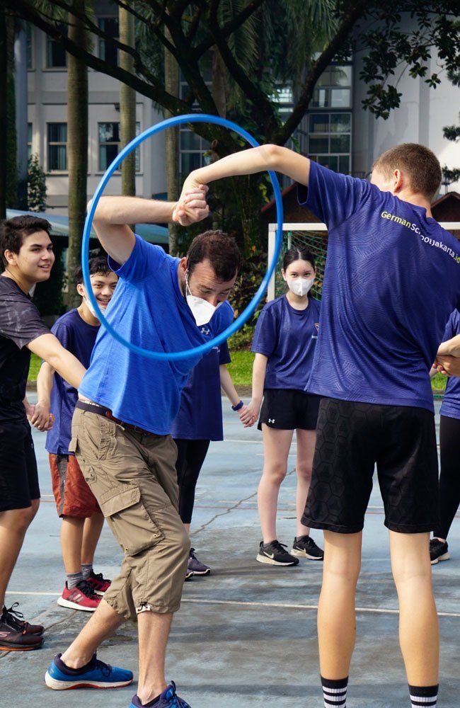 A group of people are playing with a blue hula hoop.