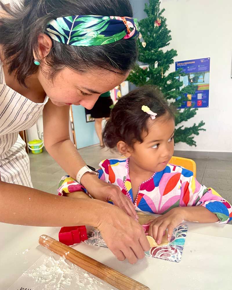 A woman and a little girl are sitting at a table with a rolling pin.