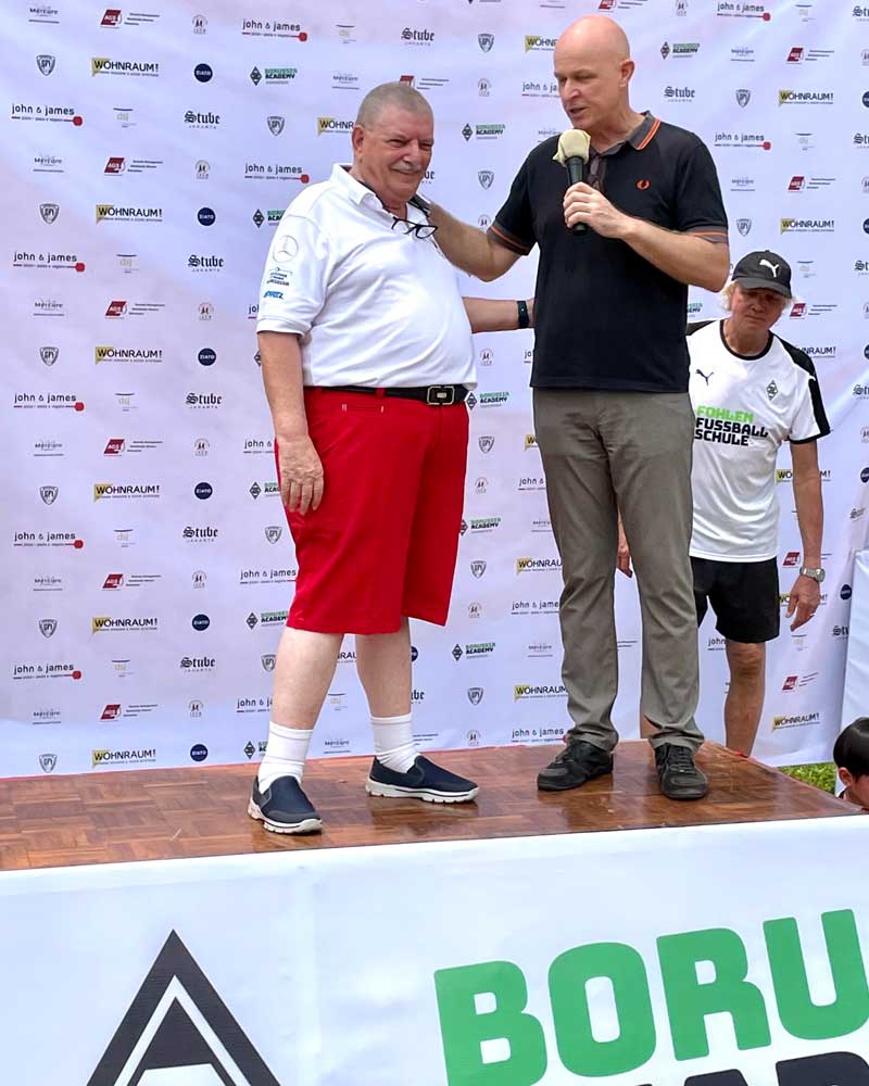 Two men are standing on a stage in front of a banner that says boru