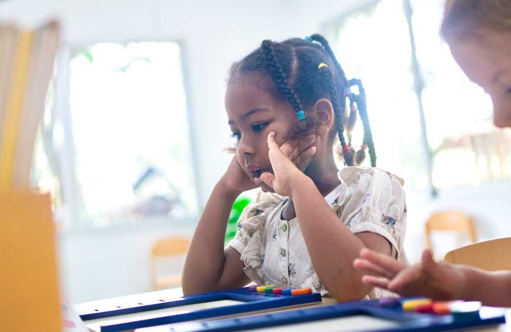 A little girl is sitting at a table playing with a toy.