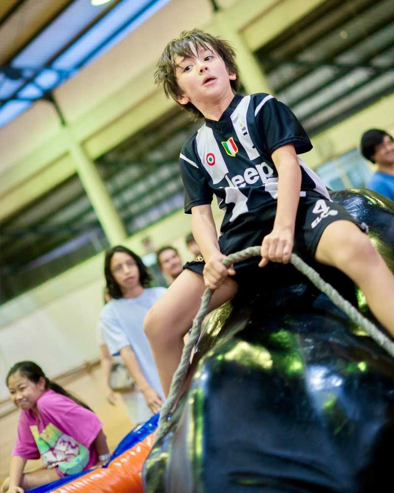 A young boy wearing a jeep jersey is riding a bull