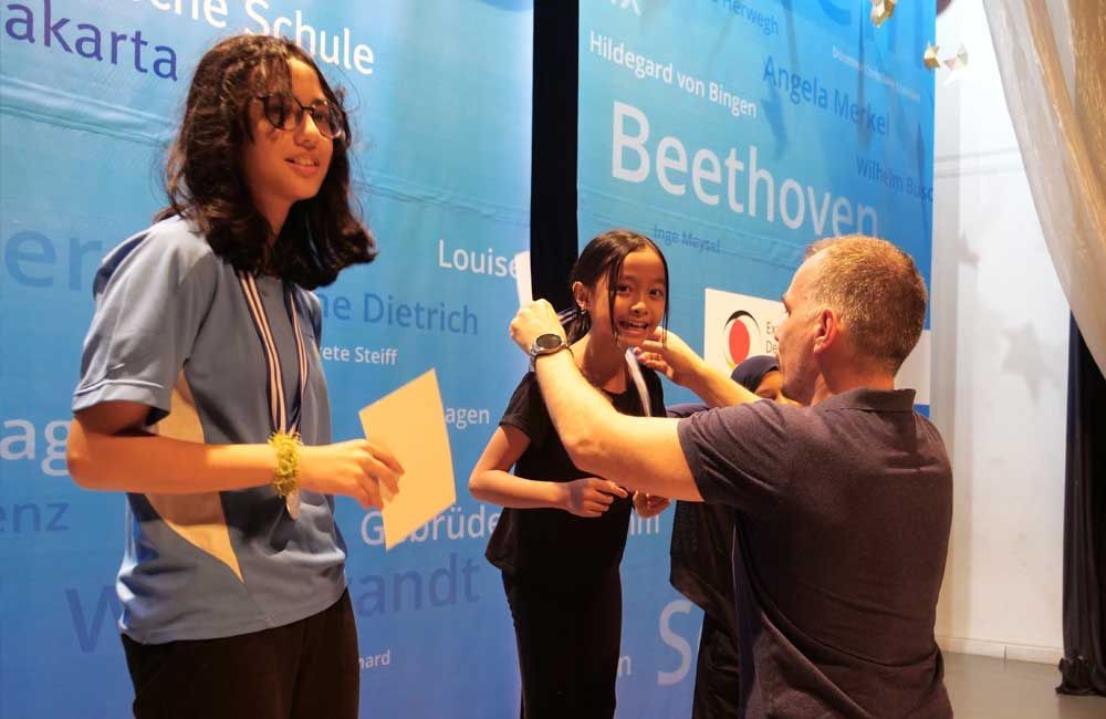 A man is putting a medal on a girl 's neck.
