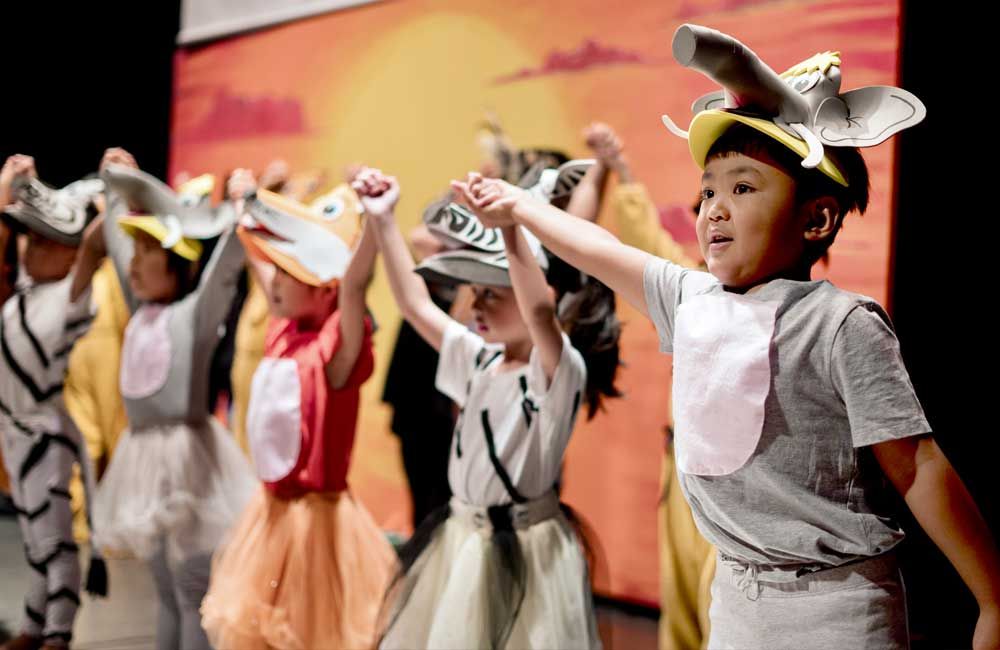 A group of children in costume are dancing on a stage.