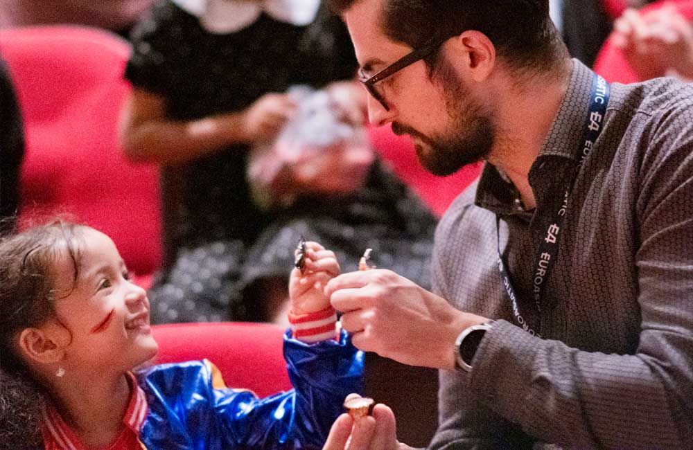 A man is feeding a little girl in a theater.