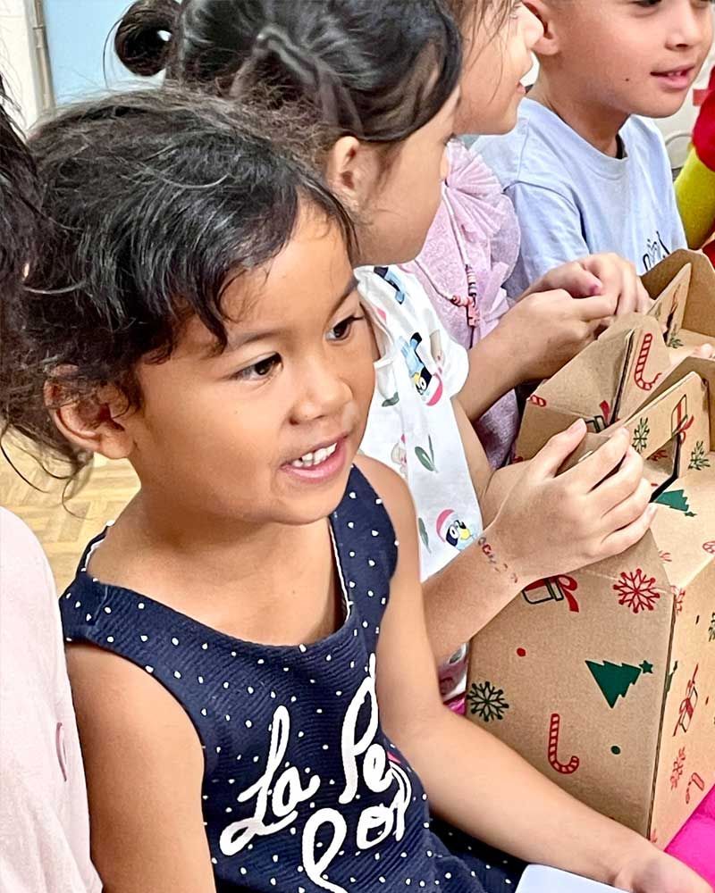 A group of children are sitting next to each other holding christmas presents.