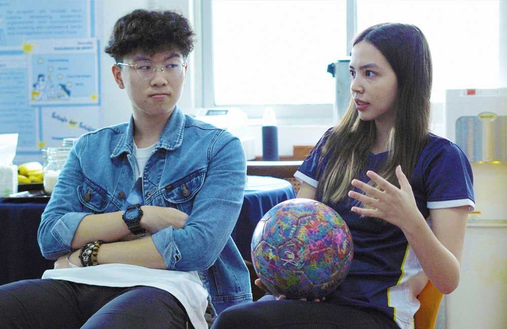 A man and a woman are sitting next to each other holding a globe.