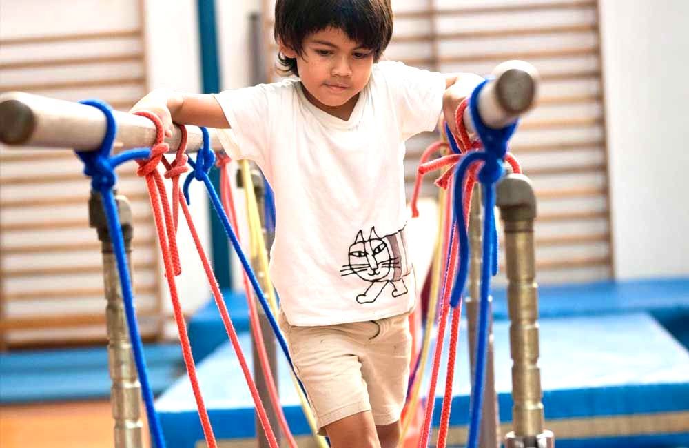 A young boy is playing with ropes in a gym.