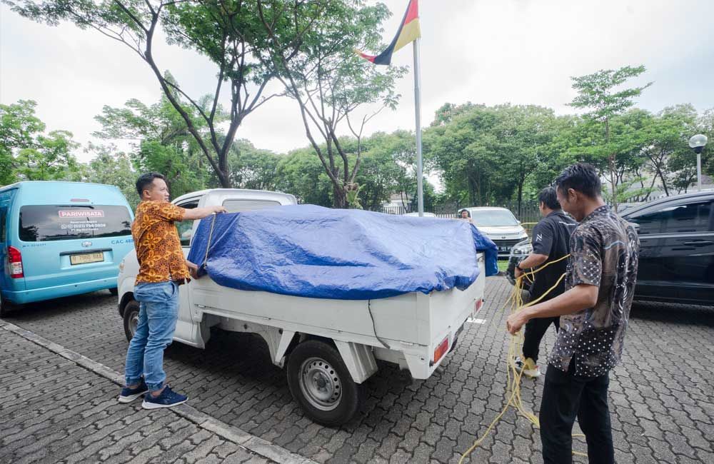 A man is covering a truck with a tarp in a parking lot.
