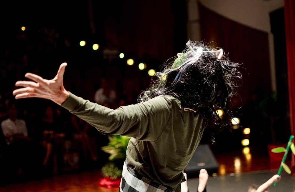 A man in a costume is standing on a stage with his arms outstretched.