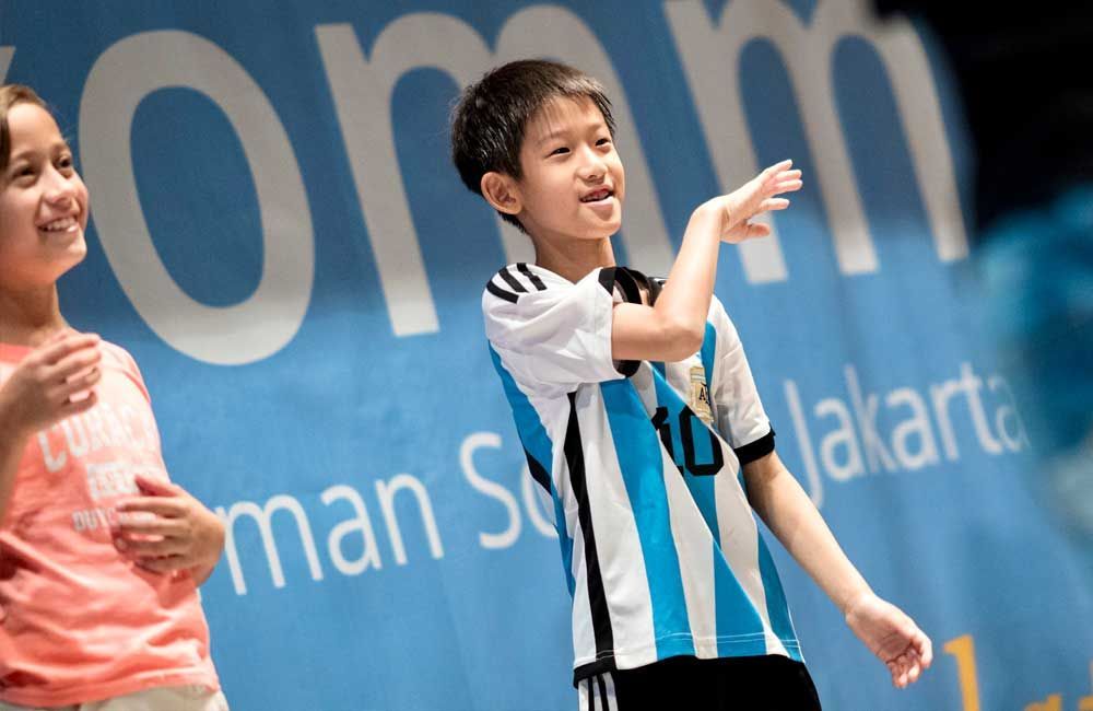 A boy and a girl are standing in front of a sign that says jakarta