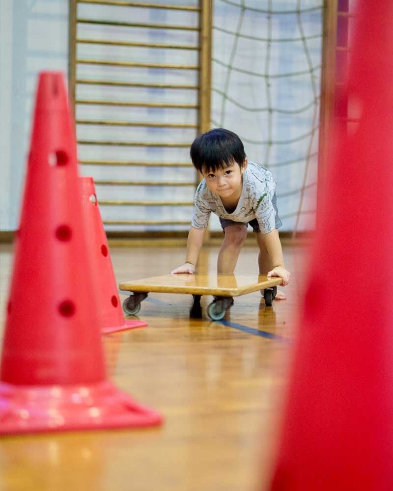 A young boy is playing with a skateboard in a gym.