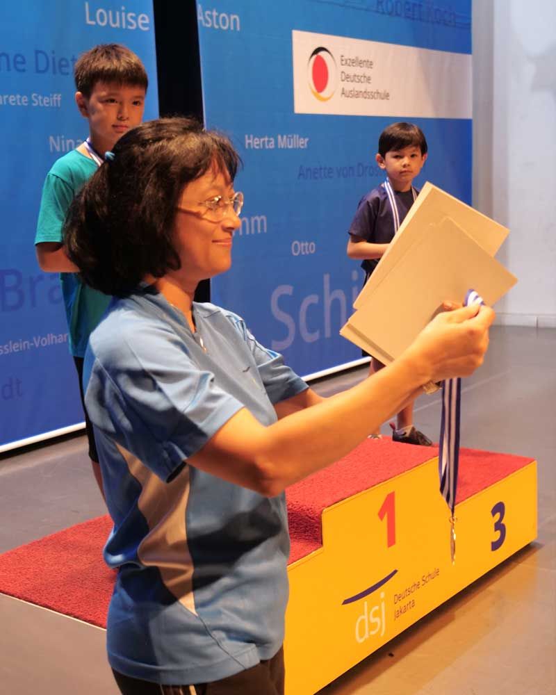 A woman stands on a podium with the number 1 on it